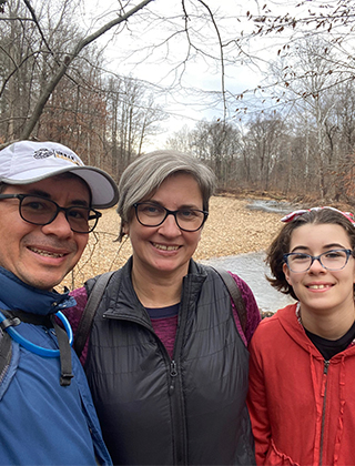 Family photo taken outdoors of Edgar with wife Gina and their daughter